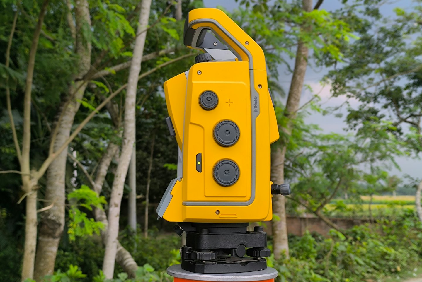 Yellow and grey total station surveying instrument mounted on a pole.